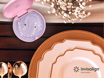The image shows a collection of tableware items including plates, bowls, and a small, pink, decorative object with a face design, set against a background that includes a wooden table, a vase with flowers, and a bottle of toothpaste branded Invisalign.